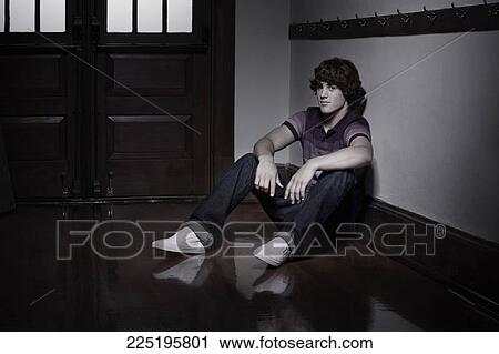 Stock Image - Teenage boy sitting in a school corridor. Fotosearch