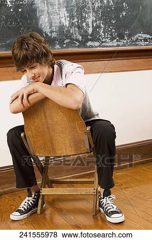 Teenage boy sitting on a chair in a classroom View Large Photo Image Stock Photo - Teenage boy sitting on a chair in a classroom. Fotosearch