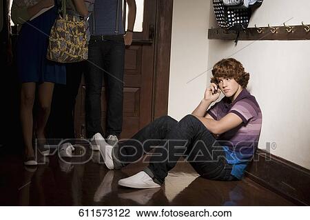 Teenage boy talking on a mobile phone with their friends in a school corridor View Large Photo Image Stock Image - Teenage boy talking on a mobile phone with their friends in a school corridor. Fotosearch