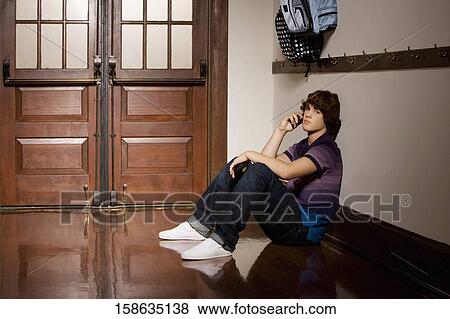 Teenage boy talking on a mobile phone in a school corridor View Large Photo Image Stock Photo - Teenage boy talking on a mobile phone in a school corridor. Fotosearch