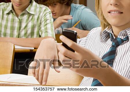 Teenage boy text messaging on a mobile phone in a classroom View Large Photo Image Stock Photo - Teenage boy text messaging on a mobile phone in a classroom. Fotosearch