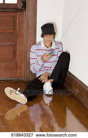 Stock Photo - Teenage boy text messaging on a mobile phone. Fotosearch