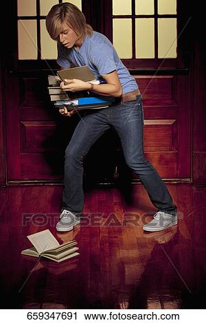 Teenage boy trying to balance books in a school corridor View Large Photo Image Stock Image - Teenage boy trying to balance books in a school corridor. Fotosearch
