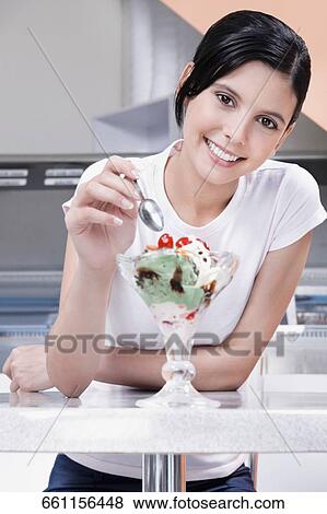 Stock Photo - Teenage girl eating an ice cream in an ice cream parlor. Fotosearch
