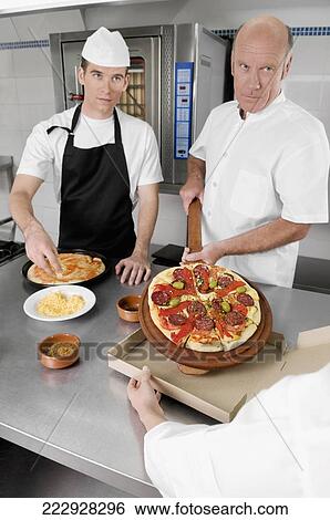 Three chefs preparing pizza in the kitchen View Large Photo Image Stock Photograph - Three chefs preparing pizza in the kitchen. Fotosearch