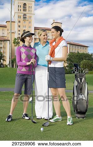 Stock Photograph - Three golfers standing in a golf course and smiling, Biltmore Golf Course, Biltmore Hotel, Coral Gables, Florida, USA. Fotosearch