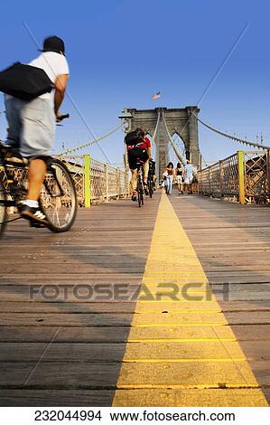 Three people riding bicycles on a footbridge View Large Photo Image Picture - Three people riding bicycles on a footbridge. Fotosearch