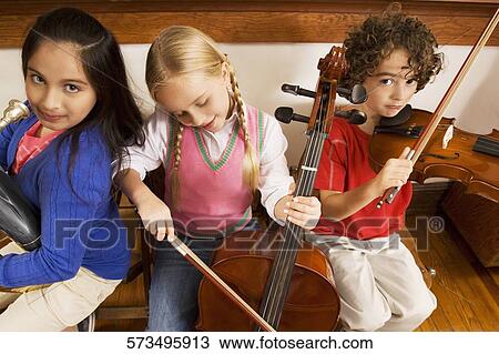 Three students playing musical instruments in a classroom View Large Photo Image Stock Image - Three students playing musical instruments in a classroom. Fotosearch