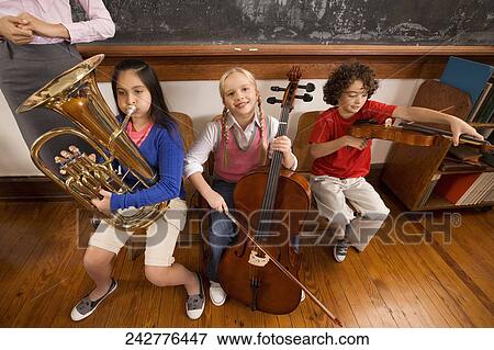Three students playing musical instruments in a classroom View Large Photo Image Stock Photo - Three students playing musical instruments in a classroom. Fotosearch