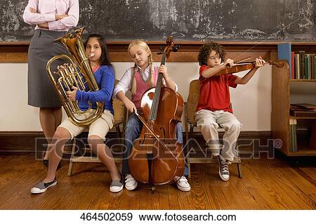 Three students playing musical instruments in a classroom View Large Photo Image Stock Photo - Three students playing musical instruments in a classroom. Fotosearch