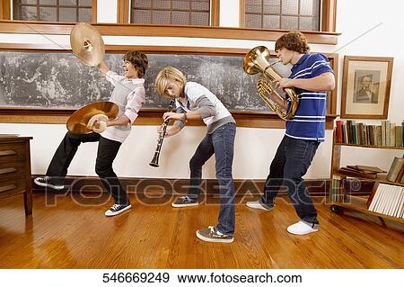 Three students playing musical instruments in a classroom View Large Photo Image Stock Photo - Three students playing musical instruments in a classroom. Fotosearch