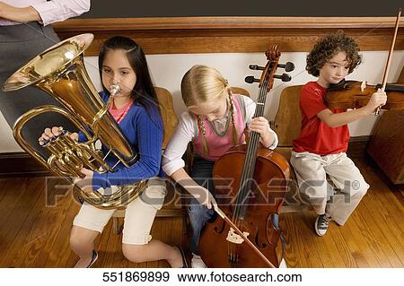 Three students playing musical instruments in a classroom View Large Photo Image Stock Photo - Three students playing musical instruments in a classroom. Fotosearch