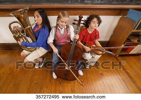 Three students playing musical instruments in a classroom View Large Photo Image Stock Photography - Three students playing musical instruments in a classroom. Fotosearch