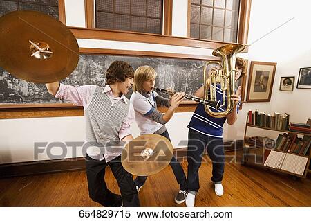 Three students playing musical instruments in a classroom View Large Photo Image Stock Photography - Three students playing musical instruments in a classroom. Fotosearch