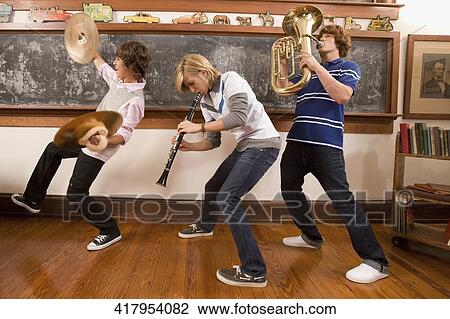 Three teenage boys playing musical instruments in a classroom View Large Photo Image Stock Image - Three teenage boys playing musical instruments in a classroom. Fotosearch