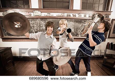 Three teenage boys playing musical instruments in a classroom View Large Photo Image Stock Photograph - Three teenage boys playing musical instruments in a classroom. Fotosearch