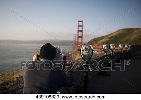 Tourist looking at a bridge through coin-operated binoculars, Golden Gate Bridge, San Francisco Bay, San Francisco, California, USA View Large Photo Image Stock Photo - Tourist looking at a bridge through coin-operated binoculars, Golden Gate Bridge, San Francisco Bay, San Francisco, California, USA. Fotosearch