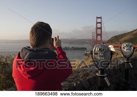 Tourist taking the picture of a bridge, Golden Gate Bridge, San Francisco Bay, San Francisco, California, USA View Large Photo Image Stock Photo - Tourist taking the picture of a bridge, Golden Gate Bridge, San Francisco Bay, San Francisco, California, USA. Fotosearch