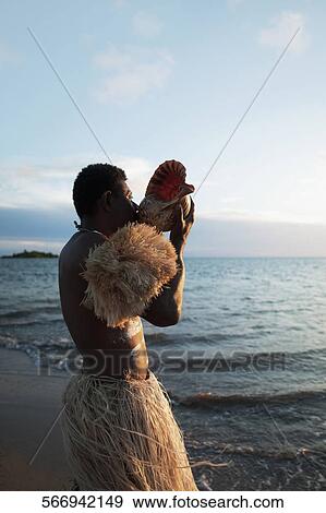 Stock Photo - Tribesman blowing a cockleshell on the beach. Fotosearch