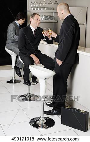 Two businessmen toasting with wine in a bar View Large Photo Image Stock Photo - Two businessmen toasting with wine in a bar. Fotosearch