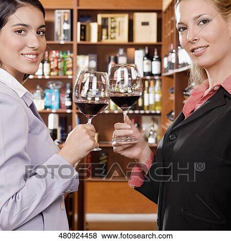 Two businesswomen toasting with wine in a bar View Large Photo Image Stock Photo - Two businesswomen toasting with wine in a bar. Fotosearch