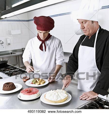 Two chefs cooking food in the kitchen View Large Photo Image Stock Image - Two chefs cooking food in the kitchen. Fotosearch