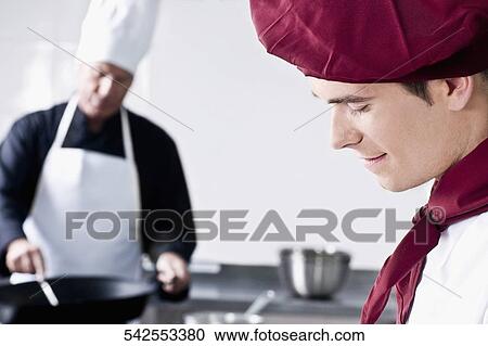 Stock Image - Two chefs cooking food in the kitchen. Fotosearch