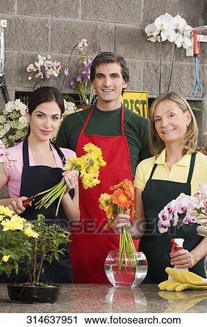 Stock Image - Two female florists with a male florist smiling. Fotosearch