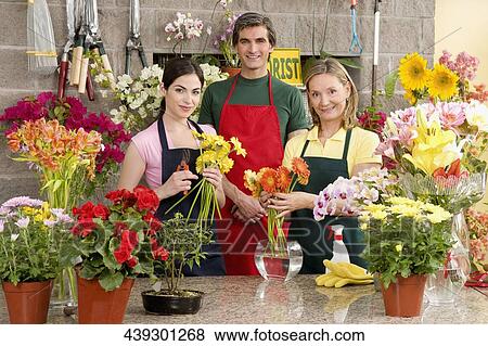 Two female florists with a male florist smiling View Large Photo Image Stock Photo - Two female florists with a male florist smiling. Fotosearch