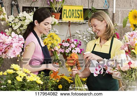 Two female florists working in a flower shop and smiling View Large Photo Image Stock Image - Two female florists working in a flower shop and smiling. Fotosearch
