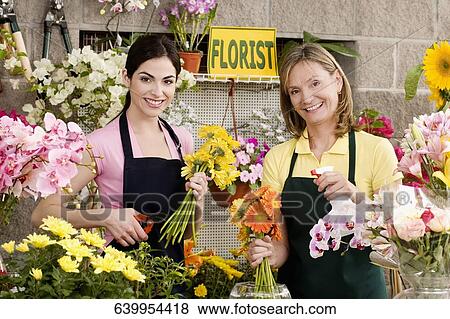 Two female florists working in a flower shop and smiling View Large Photo Image Stock Photo - Two female florists working in a flower shop and smiling. Fotosearch