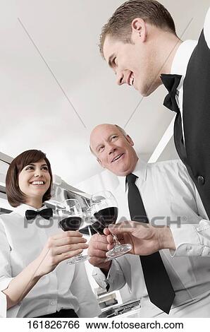 Two men and a woman toasting with wine View Large Photo Image Stock Photograph - Two men and a woman toasting with wine. Fotosearch