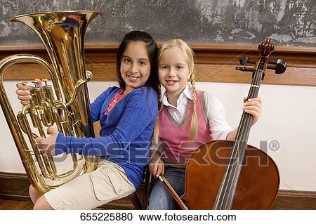 Two schoolgirls playing a cello and a tuba in a classroom View Large Photo Image Stock Image - Two schoolgirls playing a cello and a tuba in a classroom. Fotosearch