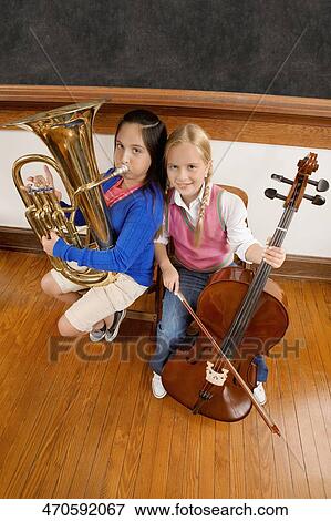 Two schoolgirls playing a cello and a tuba in a classroom View Large Photo Image Stock Photo - Two schoolgirls playing a cello and a tuba in a classroom. Fotosearch