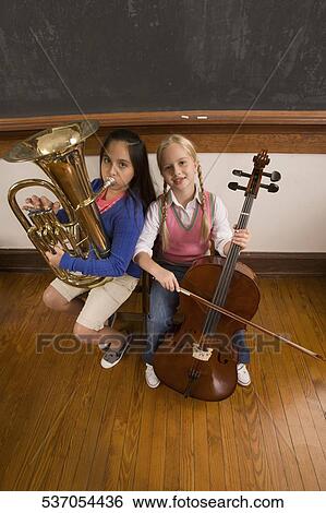 Two schoolgirls playing a cello and a tuba in a classroom View Large Photo Image Stock Photograph - Two schoolgirls playing a cello and a tuba in a classroom. Fotosearch