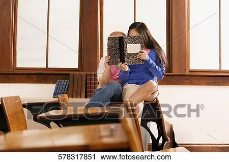Two schoolgirls reading a book in a classroom View Large Photo Image Stock Image - Two schoolgirls reading a book in a classroom. Fotosearch