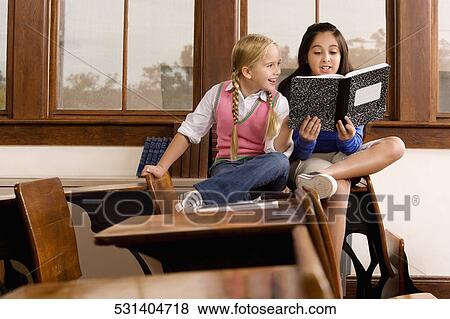 Two schoolgirls reading a book in a classroom View Large Photo Image Stock Photo - Two schoolgirls reading a book in a classroom. Fotosearch