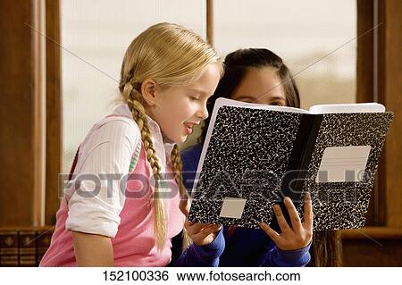 Two schoolgirls reading a book in a classroom View Large Photo Image Stock Photograph - Two schoolgirls reading a book in a classroom. Fotosearch