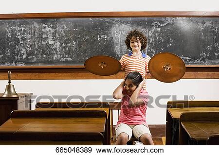 Stock Photo - Two students having fun with cymbal in a classroom. Fotosearch