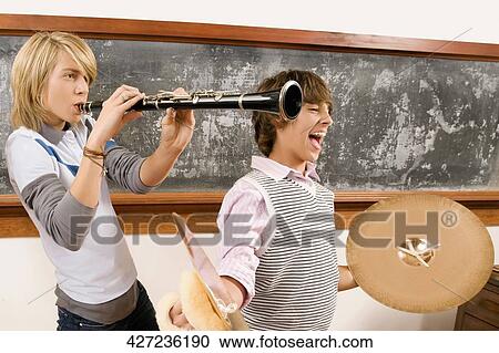 Two teenage boys playing musical instruments in a classroom View Large Photo Image Stock Image - Two teenage boys playing musical instruments in a classroom. Fotosearch