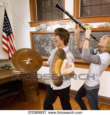 Two teenage boys playing musical instruments in a classroom View Large Photo Image Stock Photo - Two teenage boys playing musical instruments in a classroom. Fotosearch