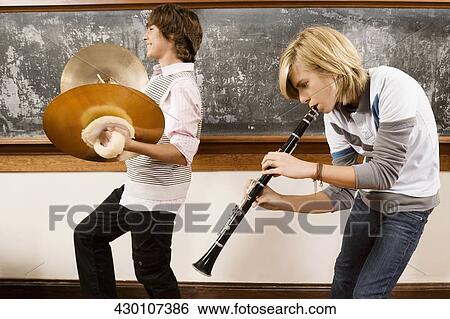 Two teenage boys playing musical instruments in a classroom View Large Photo Image Stock Photograph - Two teenage boys playing musical instruments in a classroom. Fotosearch