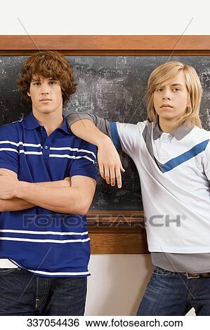 Two teenage boys standing in front of a blackboard View Large Photo Image Stock Photograph - Two teenage boys standing in front of a blackboard. Fotosearch
