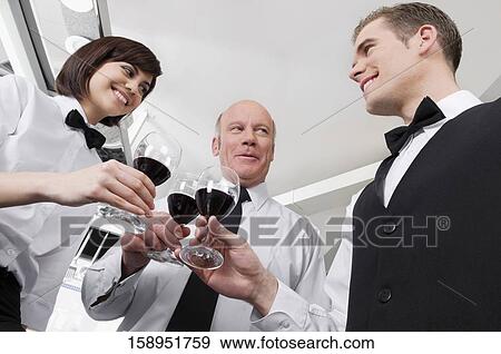 Two waiters and a waitress toasting with wine glasses View Large Photo Image Stock Photo - Two waiters and a waitress toasting with wine glasses. Fotosearch