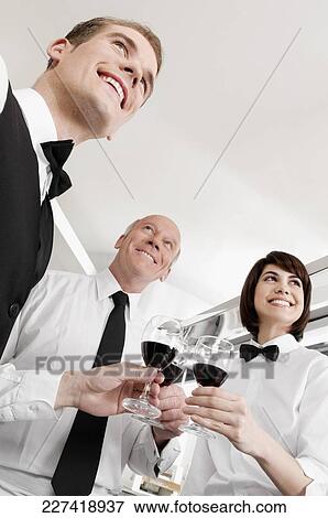 Two waiters and a waitress toasting with wine glasses View Large Photo Image Stock Photo - Two waiters and a waitress toasting with wine glasses. Fotosearch