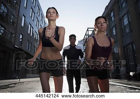 Picture - Two women and a man jogging in a street. Fotosearch