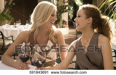 Stock Image - Two women holding drinks and smiling, Biltmore Hotel, Coral Gables, Florida, USA. Fotosearch