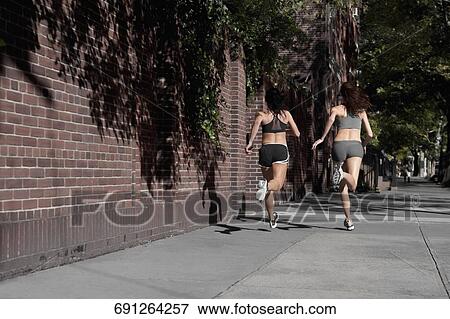 Two women jogging in a street View Large Photo Image Stock Photo - Two women jogging in a street. Fotosearch