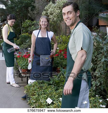 Stock Photo - Two women with a man working in a garden. Fotosearch