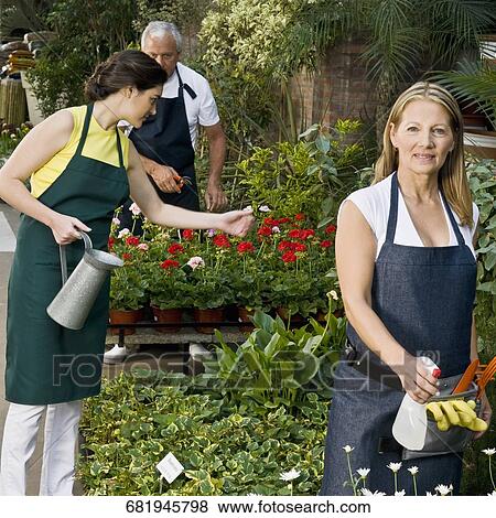 Stock Photo - Two women with a man working in a garden. Fotosearch